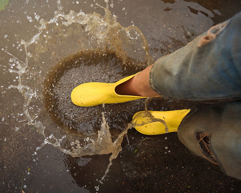 Vista desde arriba de una persona con botas de goma amarillas en una inundación. Concepto de instalación de grupos de aguas residuales.